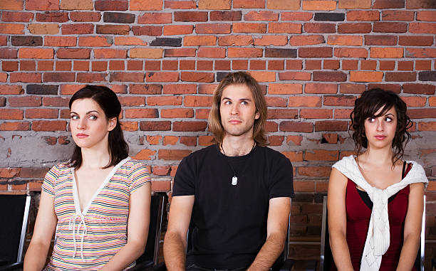 A man and two women waiting together Three person sitting in a waiting room and showing different expression. Concepts: waiting room, relationship, expression, emotions. sheepish look stock pictures, royalty-free photos & images