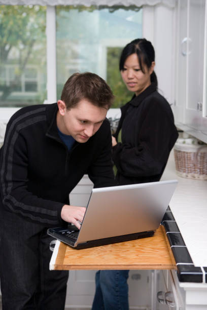 istock Asian Woman with Caucasian Man Using Laptop in Kitchen, Copyspace 172417095