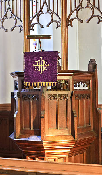 Wooden Church Pulpit A wooden church pulpit with microphone, brass lamp and purple cover,  in a modern looking church. anglican stock pictures, royalty-free photos & images