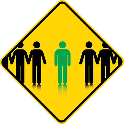 Yellow road sign containing generic stick figures with cntral figure picked out in green. The symbols are based on the AIGA Signs and Symbols produced  in the U.S. 