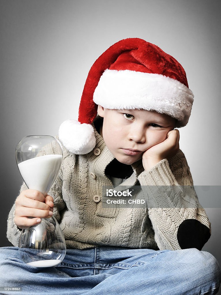 Waiting for Christmas "Unhappy boy holding a hourglass waiting for Christmas to come, some noise was added for gradient uniformity.More from Christmas related to consider:" Anger Stock Photo