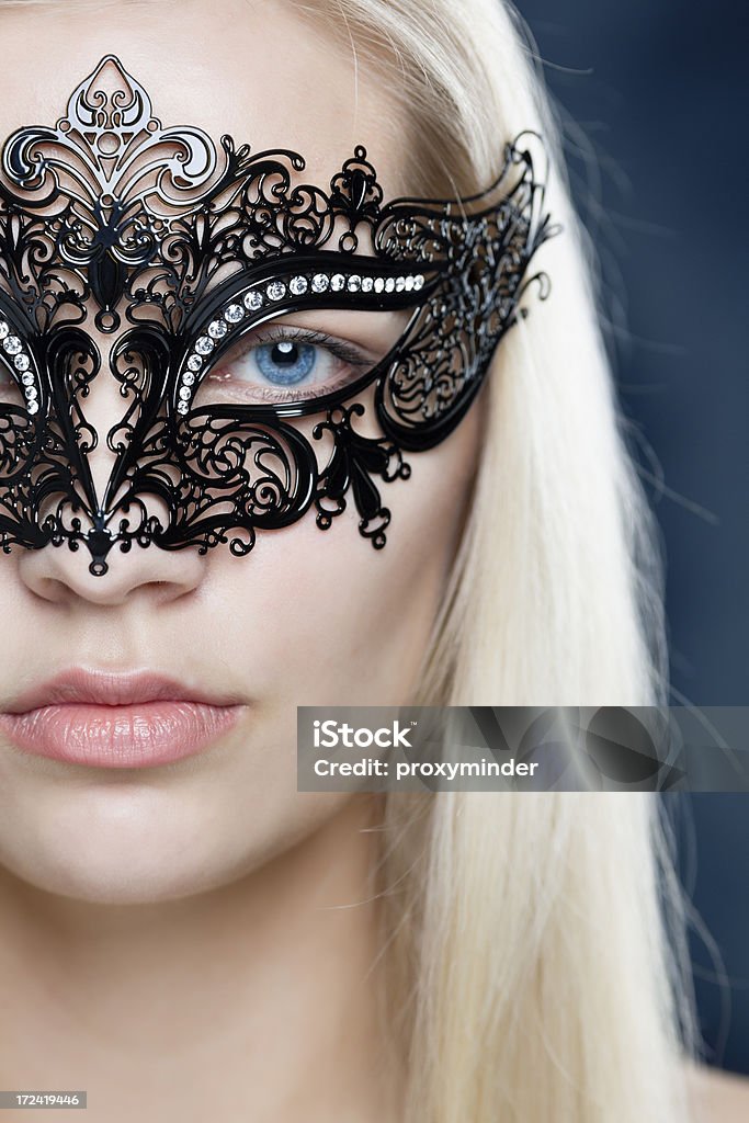 Girl face with Masquerade Mask mysterious young woman face with carnival mask portrait on blue background looking on you.  Masquerade Mask Stock Photo