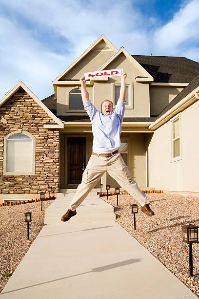 istock Enthusiastic Home Owner with Sold Sign 172420390