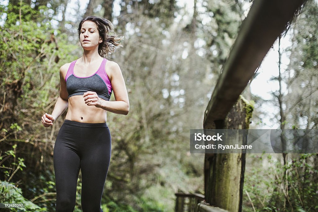 Forest Run A woman in her early 30's goes for a jog on a path through a Pacific Northwest forest.  She has a determined look on her face.  Horizontal with copy space.  30-39 Years Stock Photo