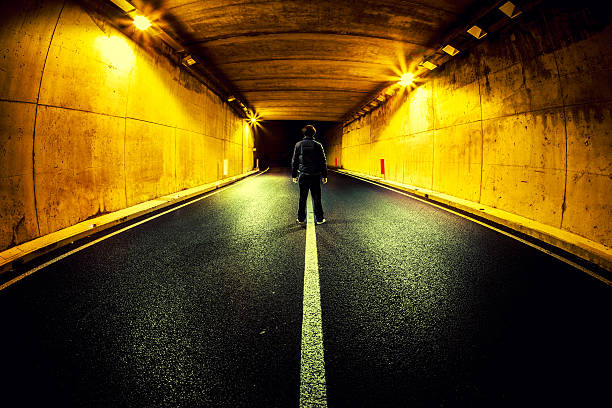 istock Man Standing Alone in Middle of Road Tunnel at Night 172420894
