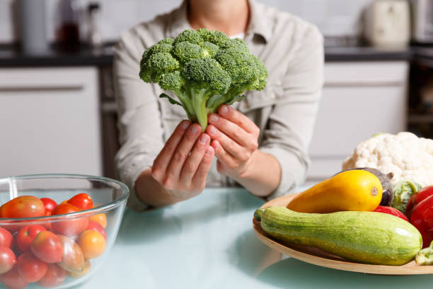 istock Female hands holding broccoli on a kitchen background together with different vegetables. 1724216492