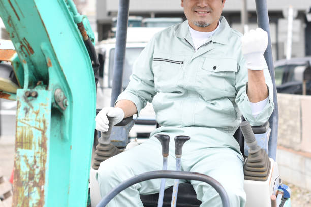 istock A middle-aged Asian male worker does a fist pump while operating construction machinery at a construction site. 1724218704