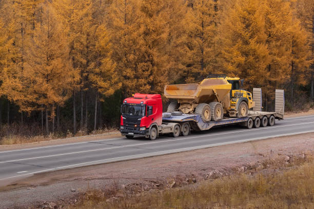 Transporting faulty heavy equipment on a platform for transportation. Close-up. Autumn road.