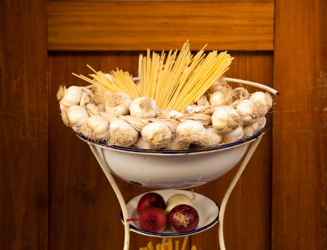 Spaghetti, garlic and onions in enameled bowl