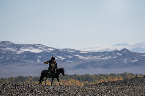 Bayan-Olgii Province, Mongolia - September 28, 2023: An ethnic Kazakh eagle hunter rides horseback on the top of a steppe.