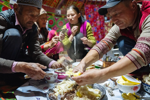 Bayan-Olgii Province, Mongolia - September 28, 2023: An ethnic Kazakh family sit down for dinner, a traditional dish called besbarmak, inside their ger (yurt).