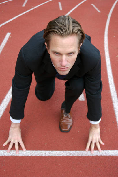 ejecutivo de crouching en primera línea en la pista de atletismo - businessman starting block business sport fotografías e imágenes de stock