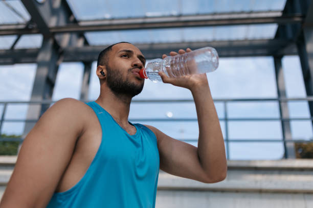 istock Well-built handsome sportsman drinking water after workout 1724239146