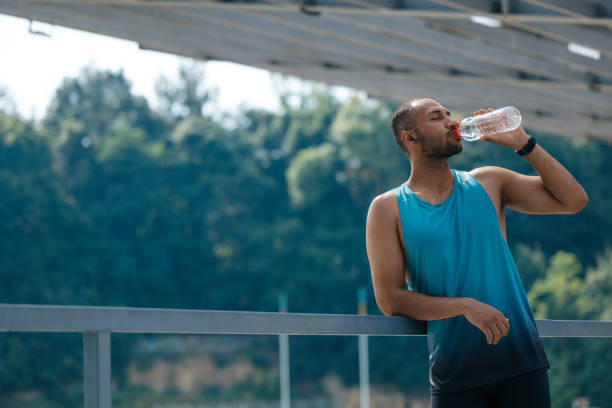 istock Well-built handsome sportsman drinking water after workout 1724239174