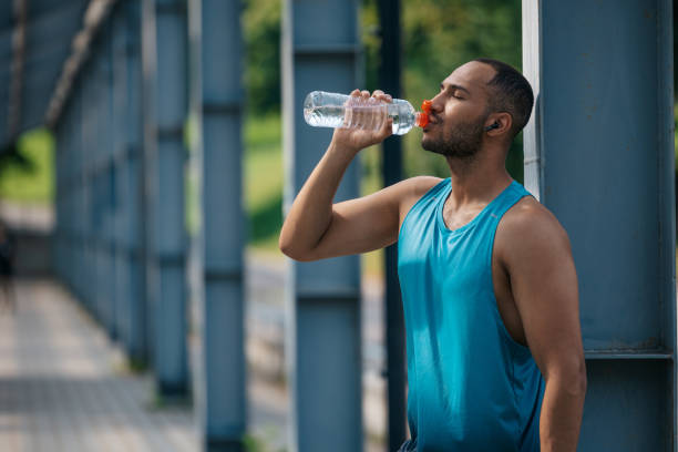 istock Well-built handsome sportsman drinking water after workout 1724239183