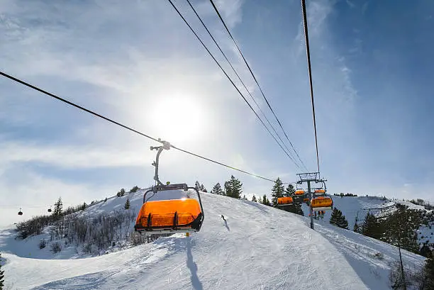 "Park City, Utah orange covered ski lifts with sun on sunny day.  Riding up chairlift late in the afternoon.  Captured as a 14-bit Raw file. Edited in 16-bit ProPhoto RGB color space."