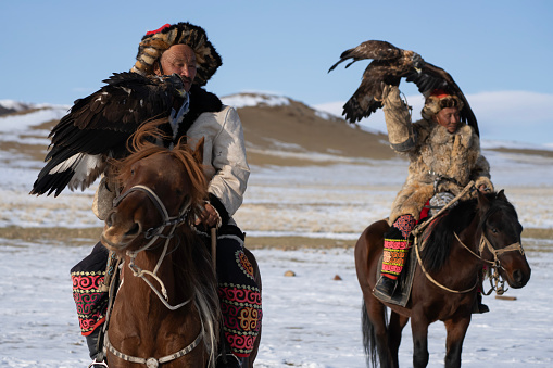 Bayan-Olgii Province, Mongolia - September 30, 2023: Ethnic Kazakh eagle hunters riding with golden eagles tethered to arm at a local Golden Eagle Festival.