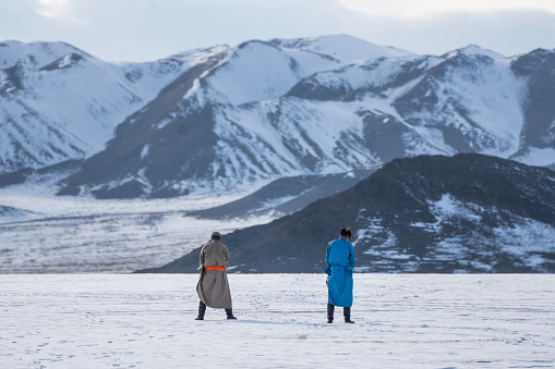 Bayan-Olgii Province, Mongolia - September 30, 2023: Two people taking a bathroom break in front of steppes at the Ulgii Golden Eagle Festival.