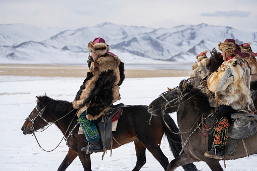 Bayan-Olgii Province, Mongolia - September 30, 2023: Ethnic Kazakh eagle hunters ride with golden eagles tethered to their arms at a local Golden Eagle Festival.