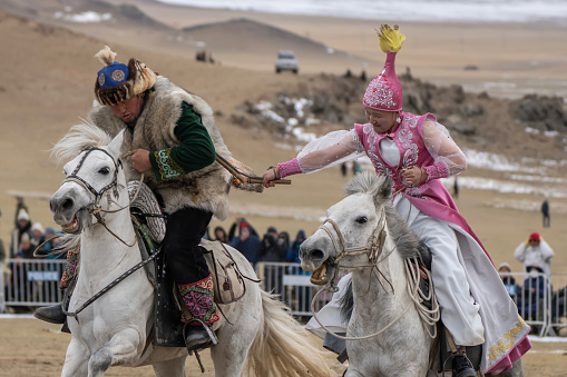 Bayan-Olgii Province, Mongolia - October 1, 2023: An ethnic Kazakh woman in a traditional costume whips her partner in a game called \