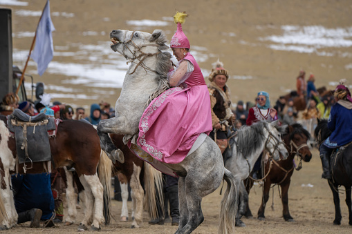 Bayan-Olgii Province, Mongolia - October 1, 2023: A horse bucks as a woman in a traditional Kazakh costume rides it at the Golden Eagle Festival.