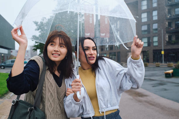 istock Young women staying dry under a clear rain umbrella 1724262314