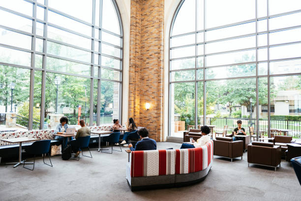 istock University students in campus, sitting in lobby with large windows and doing different activities - listening to music, eating snack, working on laptop or drinking coffee 1724262876