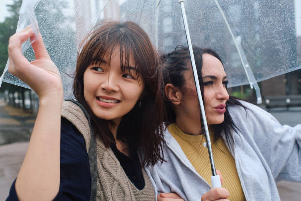 istock Two young women sheltering from the rain under an umbrella 1724262903