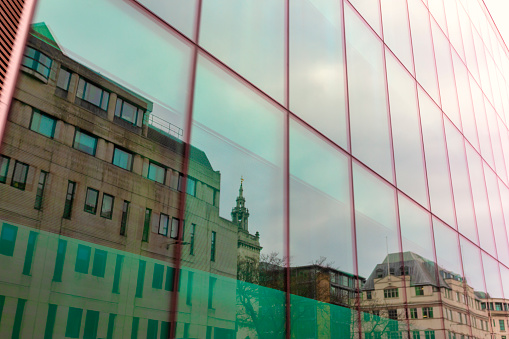 An abstract mirrored row of houses in the windows of a modern office building.