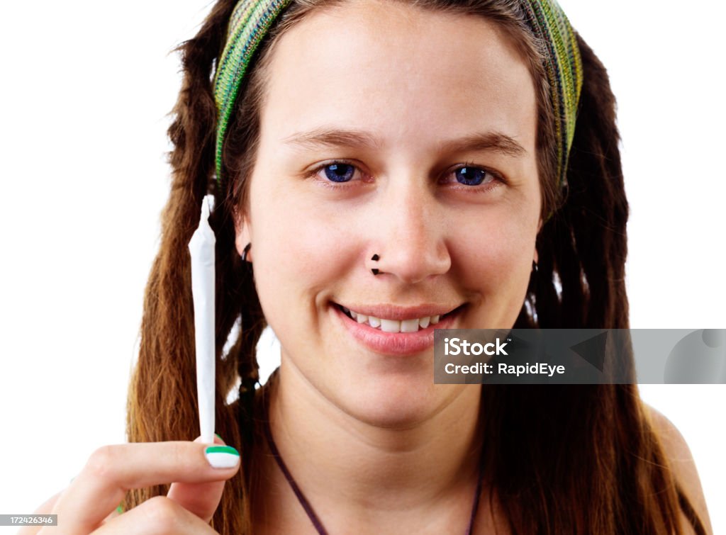 Beautiful young hippie offers hand-rolled joint of marijuana "A pretty young woman with pierced nose and dreadlocks holds out a hand-rolled joint of marijuana, offering it and smiling." 20-29 Years Stock Photo