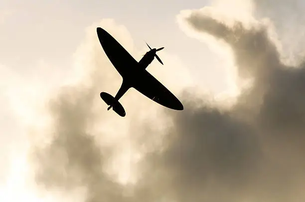 Spitefire aeroplane silhoutted against grey clouds