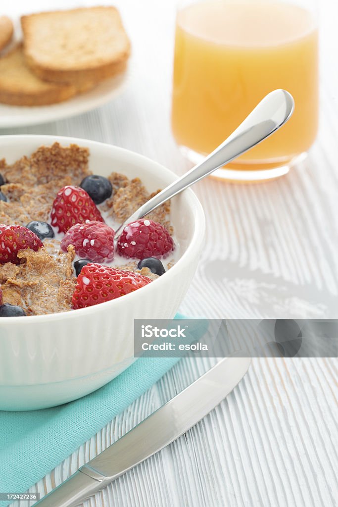 Healthy breakfast "Bran cereal bowl with strawberries, cranberries, raspberries and milk. Toast bread and orange juice on the table too." Bowl Stock Photo