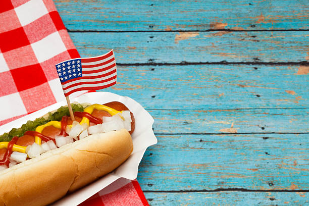 Patriotic Hotdog Ketchup, mustard, relish and onions on a hot dog with flag. relish stock pictures, royalty-free photos & images