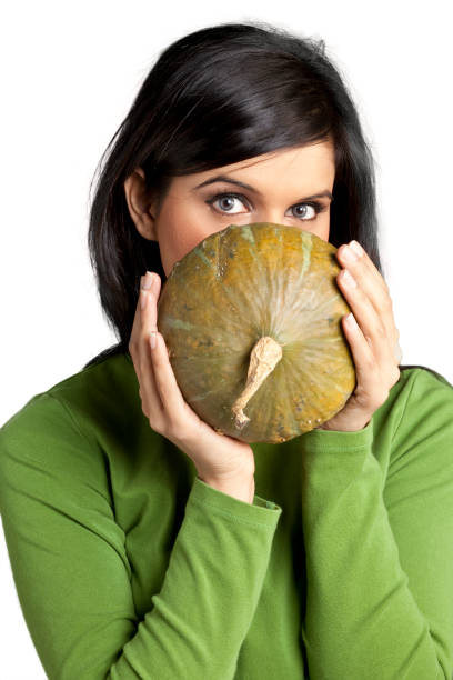 Studio shot of a woman holding a gourd in front of her face.