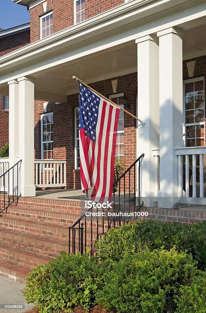 American flag hanging off porch column - Royaltyfri Amerikanska flaggan Bildbanksbilder American flag hanging off porch column - Royaltyfri Amerikanska flaggan Bildbanksbilder