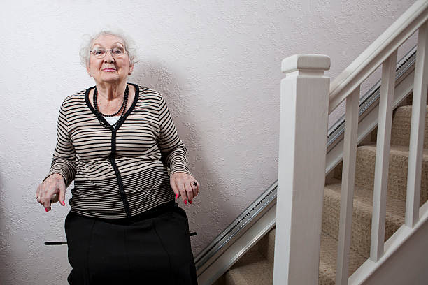 An elderly lady using a stairlift stock photo