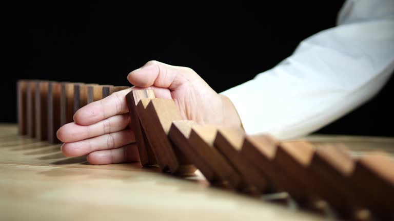 Domino Effect, Inflation Financial Crisis. Business leader hand stopping wooden domino protect crisis effect. Concept of Risk, Assessment, Insurance, Security, Financial, Recession, Business