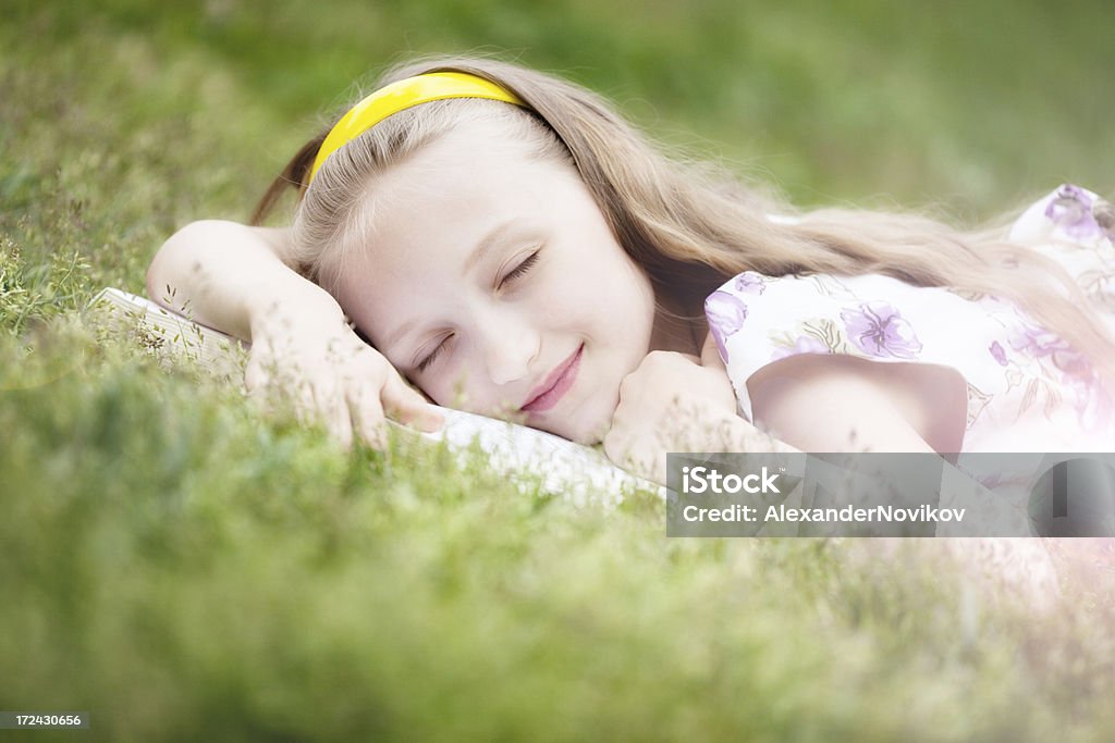 Scivolare carina ragazza sdraiata sul libro - Foto stock royalty-free di 10-11 anni