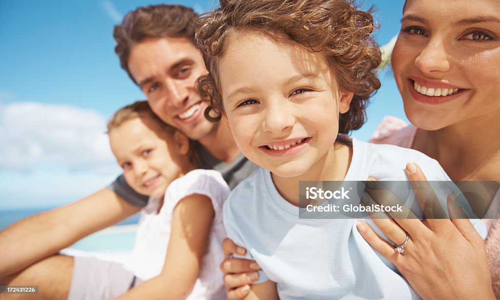 A picture of a family sitting outside Cute young family smiling together while outdoors Adult Stock Photo