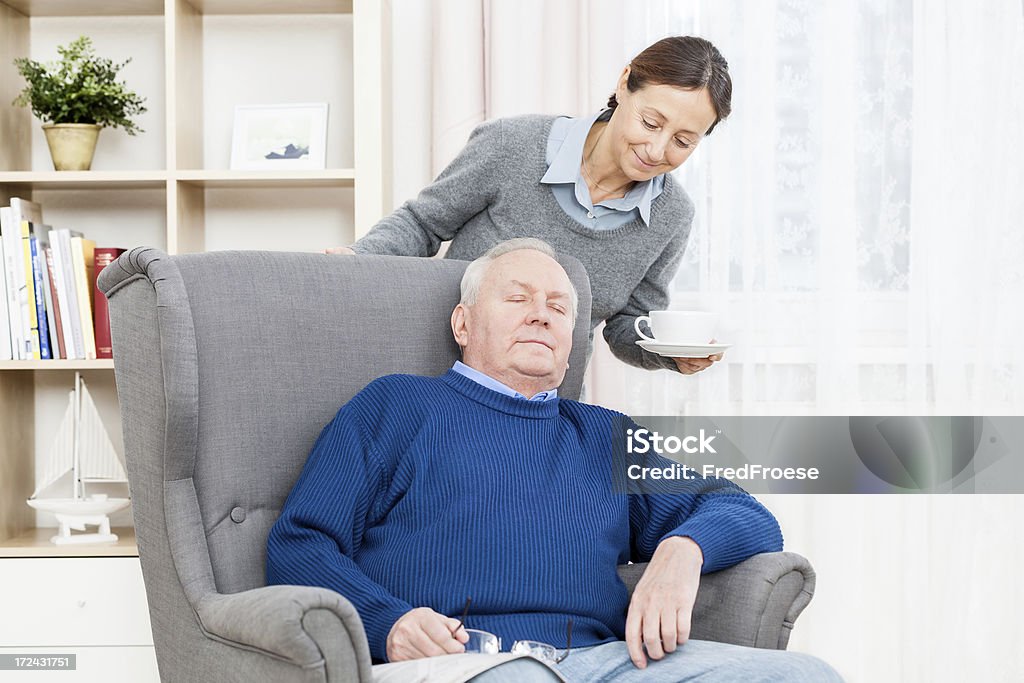 Senior Man Resting In Chair Senior Man Resting in a Wing Chair with Caregiver Daughter Stock Photo