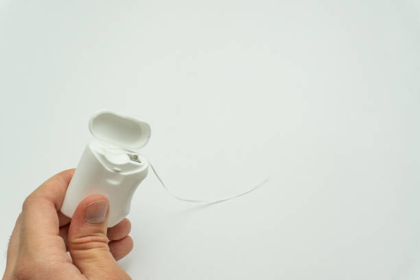 istock Male hand holding dental floss on white background copy space 1724318295