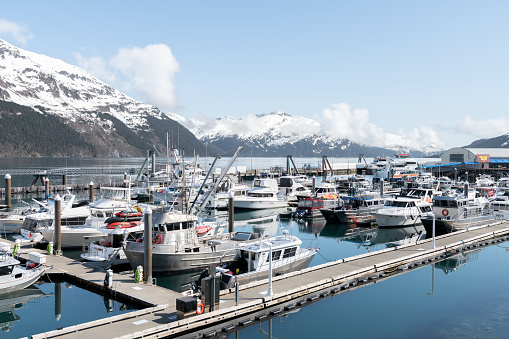 Pleasure and Fishing boats in Whittier marina with clouds and mist hanging on the mountains behind, Alaska, USA