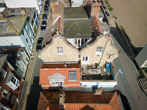 Drone view of the roof tops of terraced townhouses located near the beachfront of the popular coastal town. The narrow streets and parked cars are visible.