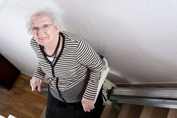 Senior Lady Uses A Stair Lift To Help Her Disability stock photo