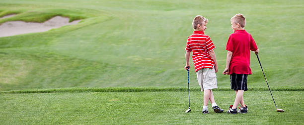 Junior Golf A couple of young boys bonding on the golf course. Friendship theme. junior level stock pictures, royalty-free photos & images