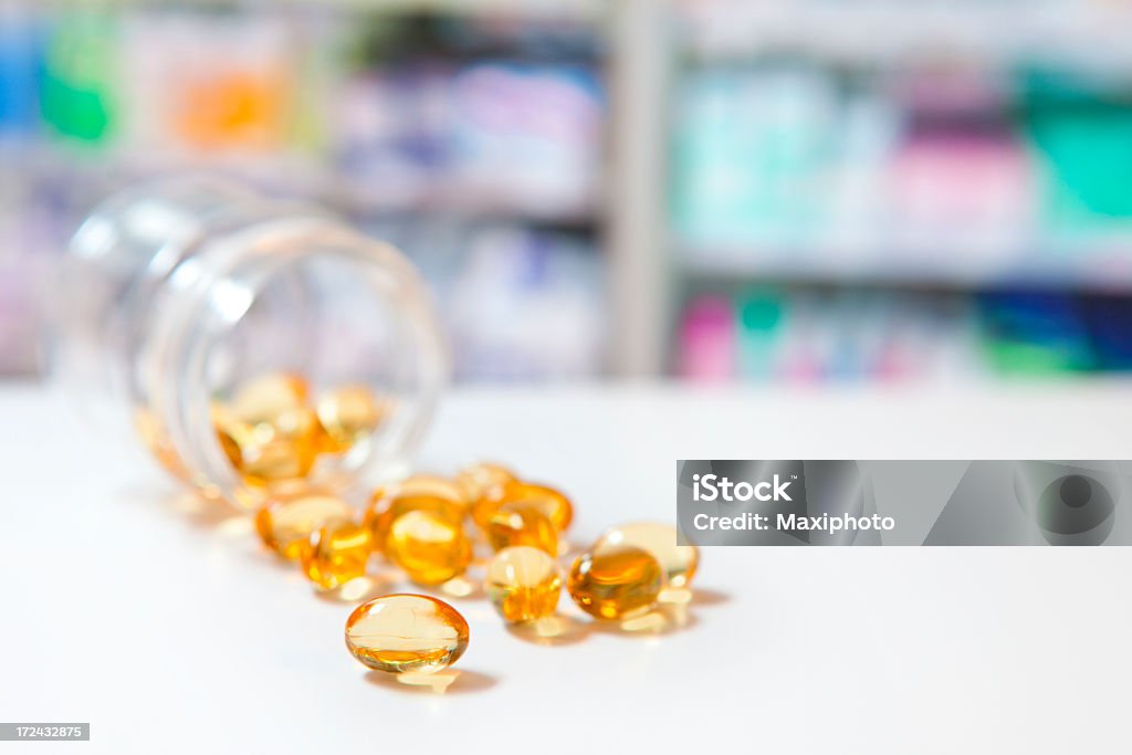 Vitamina gel pastillas vertiendo de botella en medicina, droguería que quieran en el estante - Foto de stock de Amarillo - Color libre de derechos
