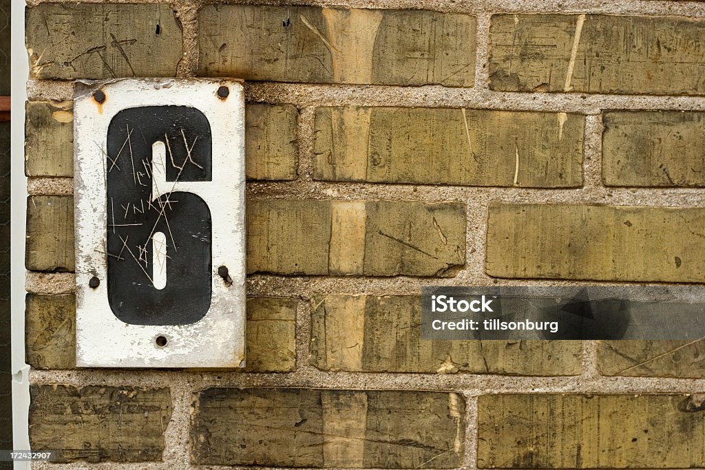 Black number 6 posted on white on a rough brick wall Number six on sign mounted on brickwall. Number 6 Stock Photo