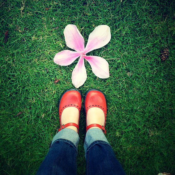 Bright red shoes next to a flower made of magnolia petals, from a personal perspective.  Photo captured with an iPhone.