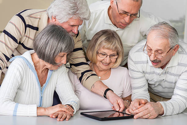 gruppo di anziani esaminare digital tablet - senior adult group therapy social gathering community center foto e immagini stock