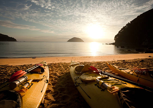 Sea kayaks on beach at dawn, Abel Tasman, New Zealand stock photo